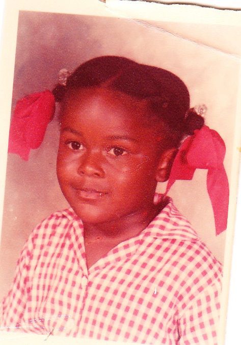 A young girl with pigtails and a red bow in her hair.