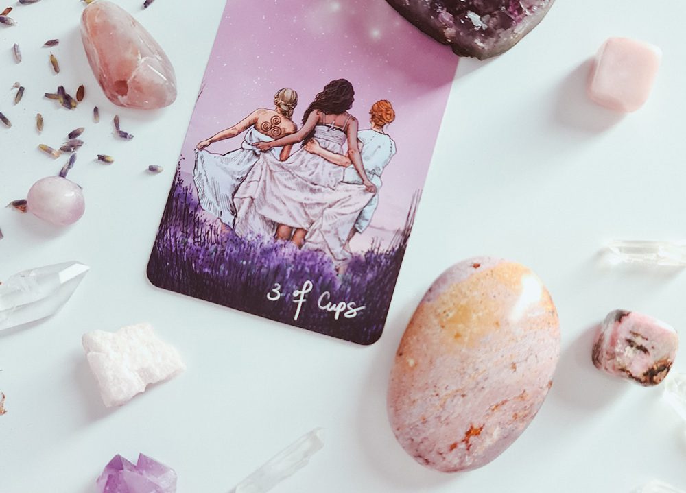 A tarot card sitting next to some rocks and crystals.